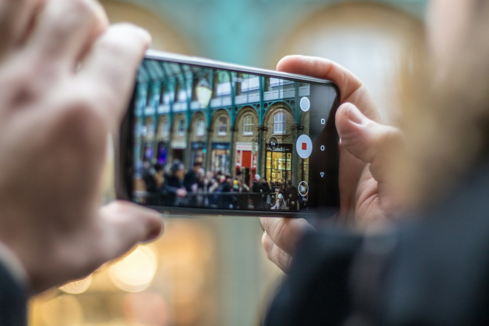 person holding smartphone taking video of people